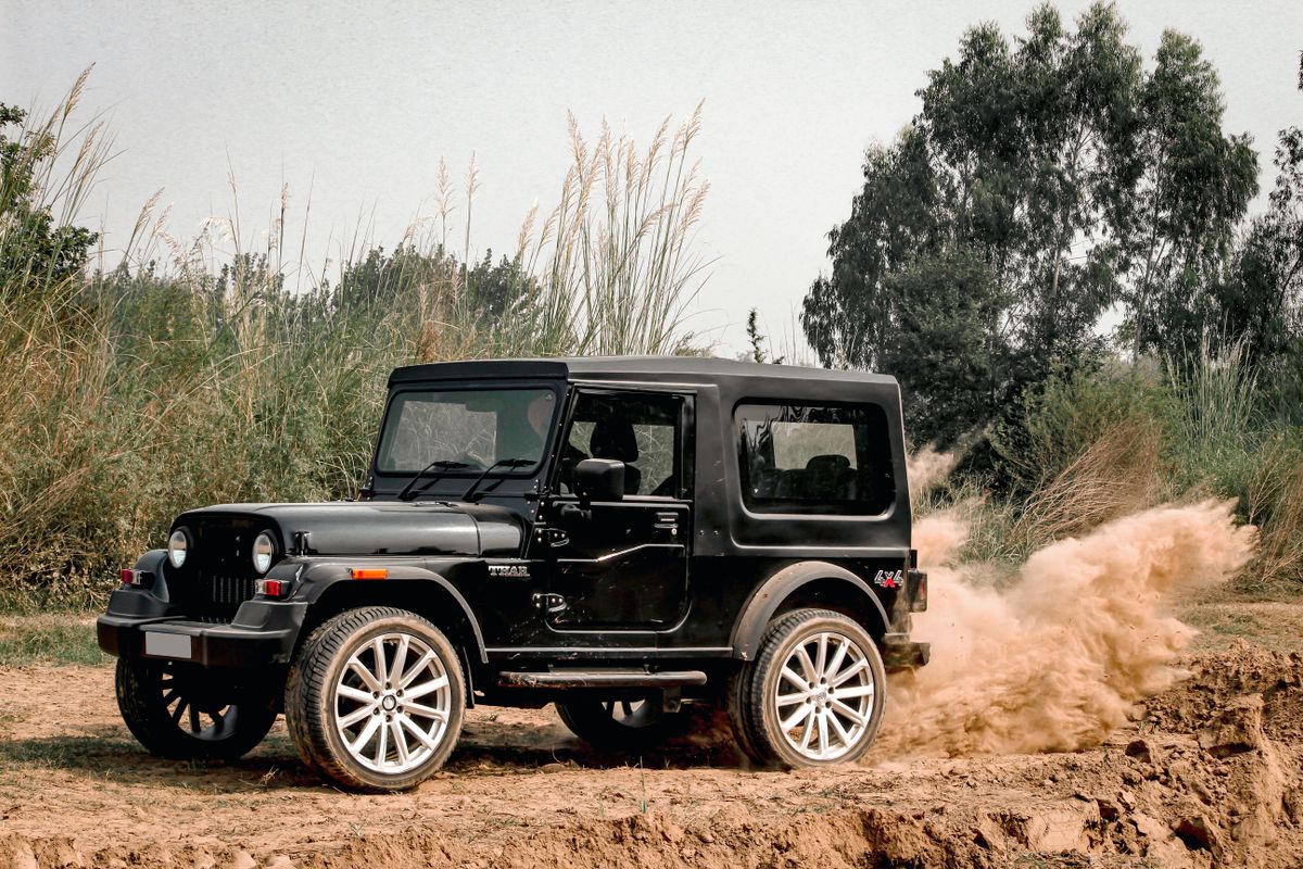 Mahindra Thar 4x4 SUV kicking up dust while off-roading, available for self-drive rental in Manali
