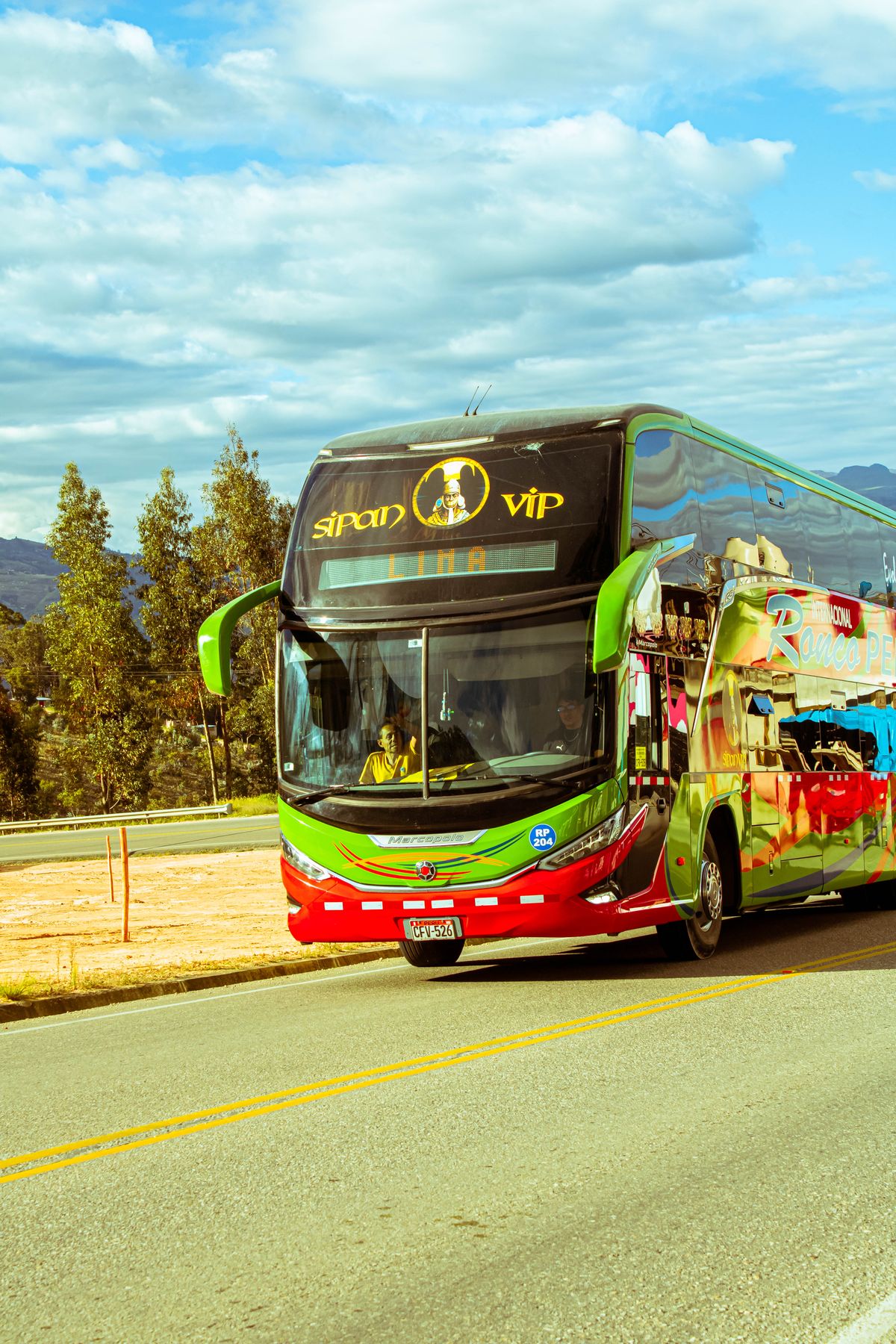 Colorful tourist coach bus travelling on a scenic highway with mountains in view